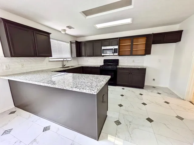 a kitchen with granite countertop a sink and a stove top oven