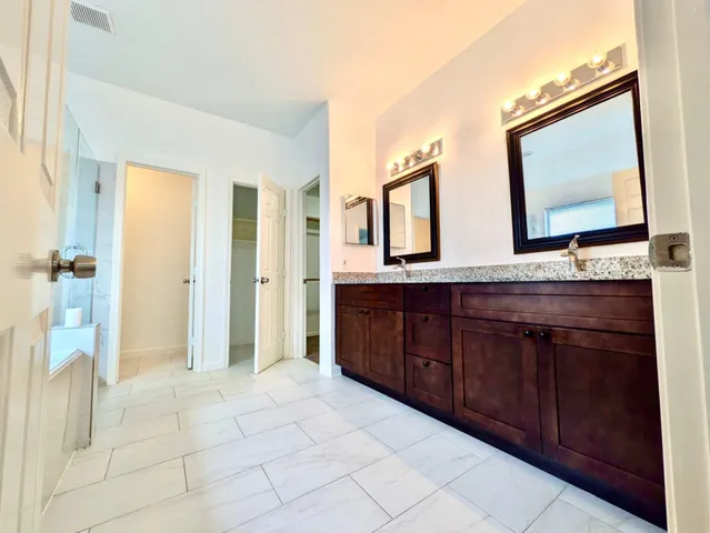 a bathroom with a granite countertop sink a mirror and a shower
