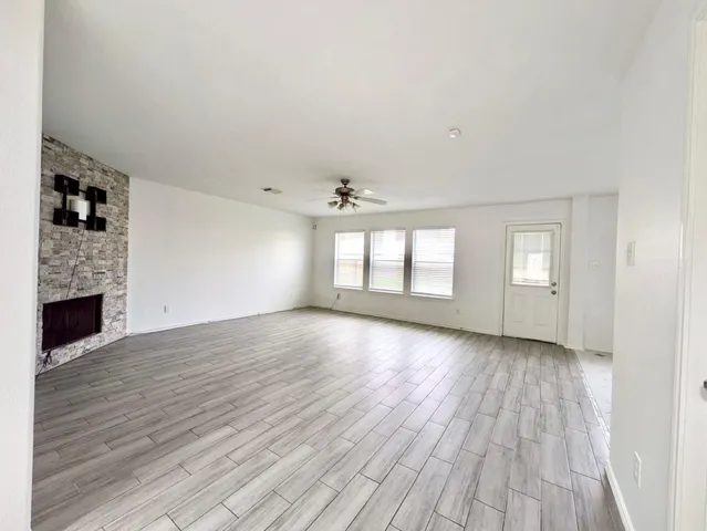 an empty room with wooden floor fireplace and windows