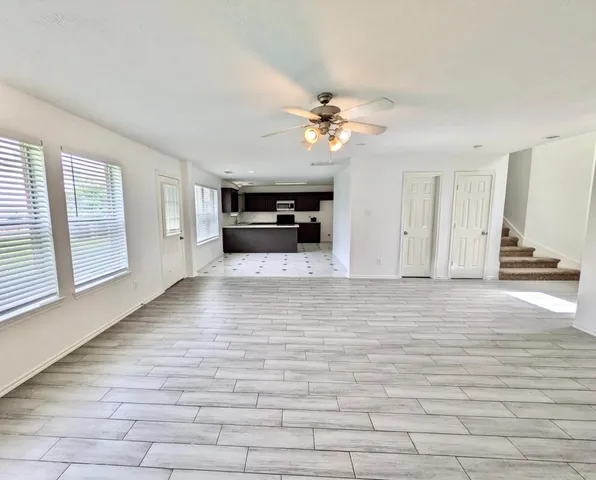 a view of an empty room with a window and kitchen view