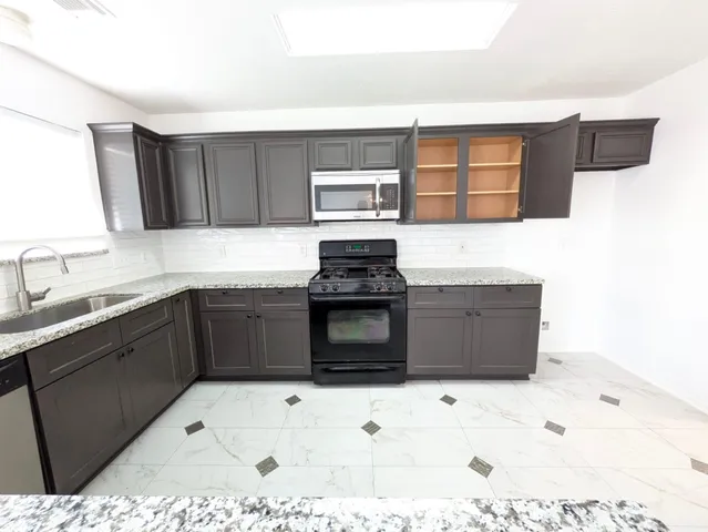 a kitchen with granite countertop a stove top oven sink and cabinets