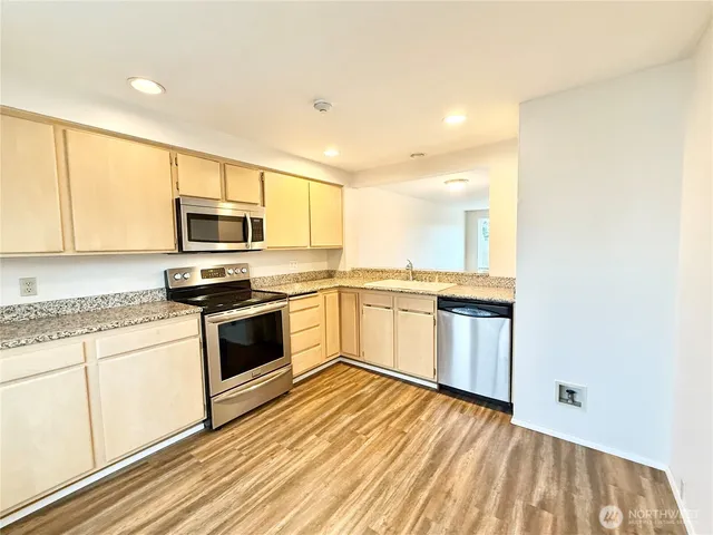 a kitchen with stainless steel appliances granite countertop a stove a sink and a microwave