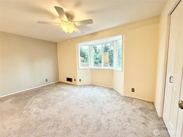 an empty room with a window and a ceiling fan