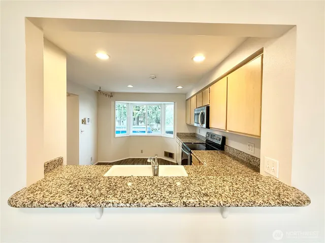 a kitchen with granite countertop a stove top oven sink and cabinets