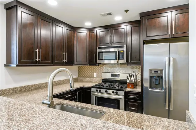 a kitchen with granite countertop stainless steel appliances and refrigerator