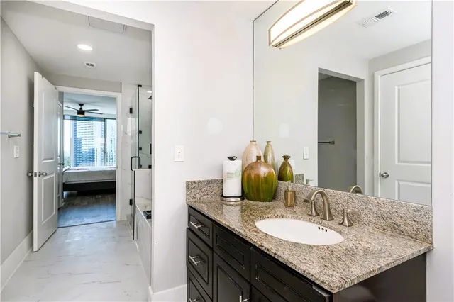 a en suite bathroom with a granite countertop sink and a mirror