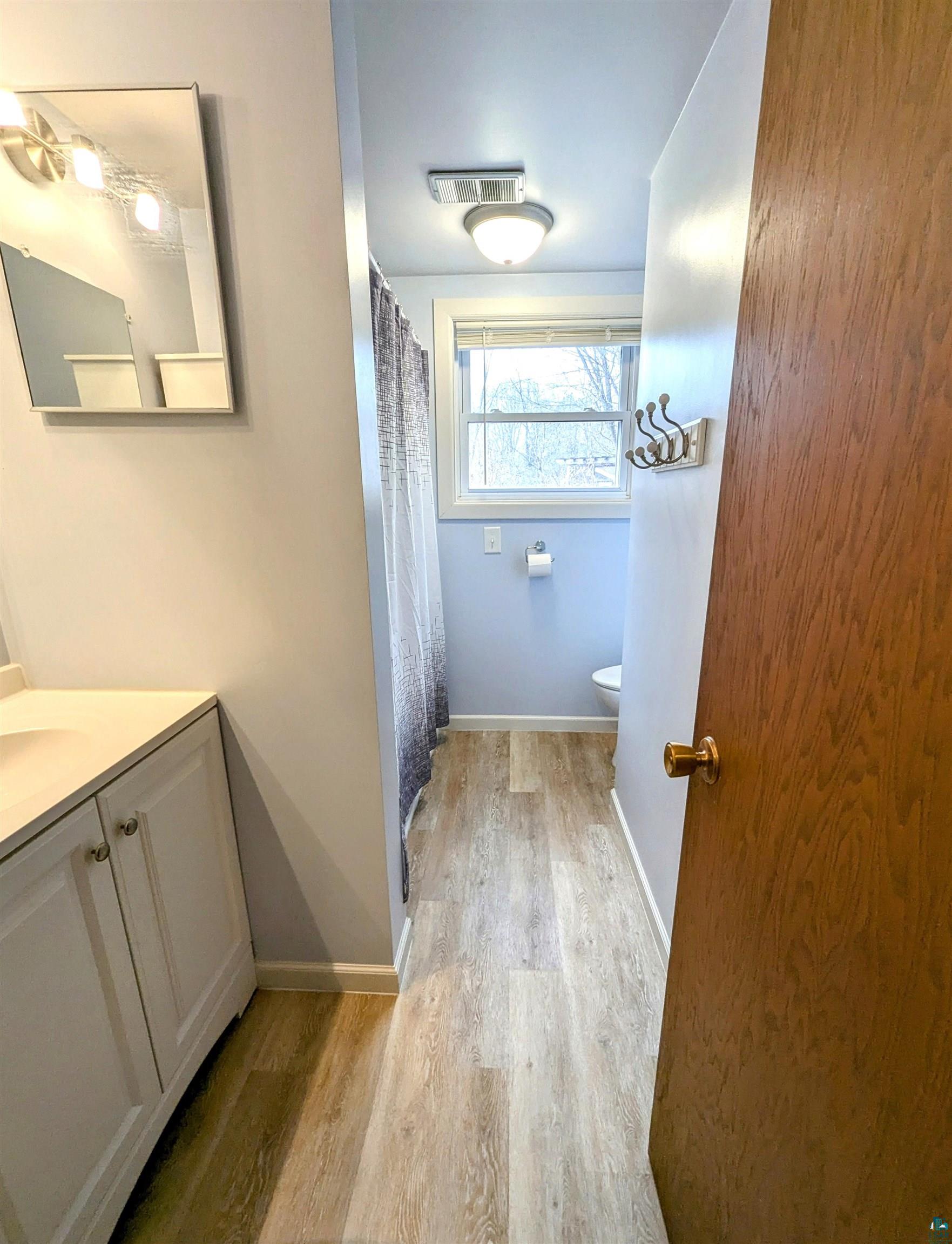 3321 Decker Road Duluth, MN 55811 - Photo 24 of 31 Bathroom with vanity, wood finished floors, visible vents, baseboards, and toilet