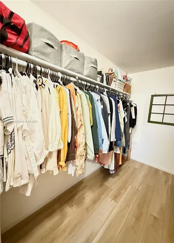 a view of walk in closet with clothes and shoes