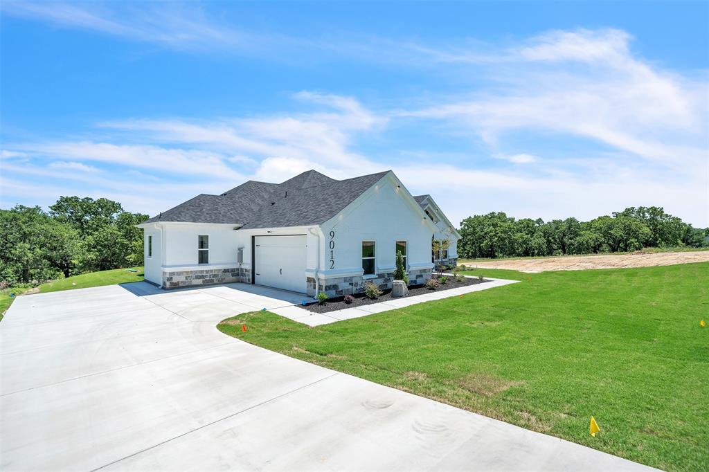 a view of a house with a big yard plants and large tree