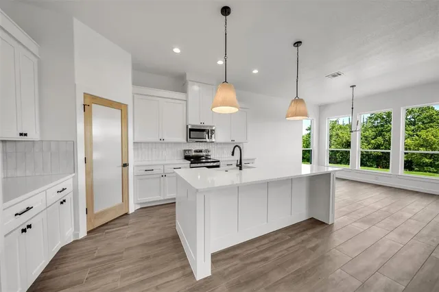 a large kitchen with kitchen island a stove a sink a center island and wooden floor