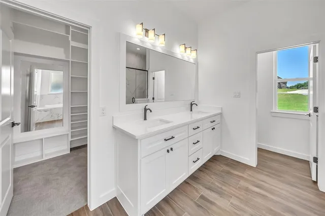 a bathroom with a double vanity sink a mirror and a bathtub