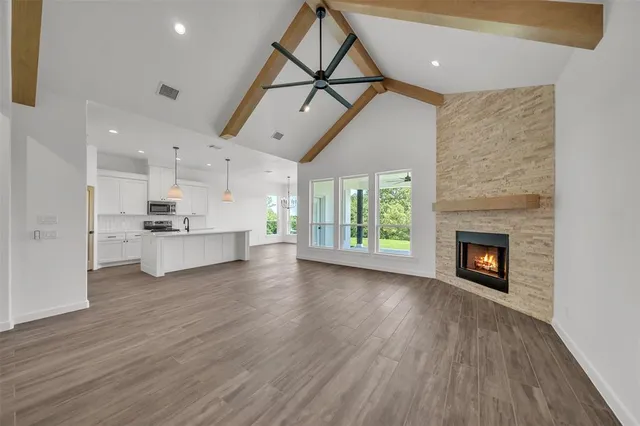 a view of a kitchen and an empty room with wooden floor a fireplace