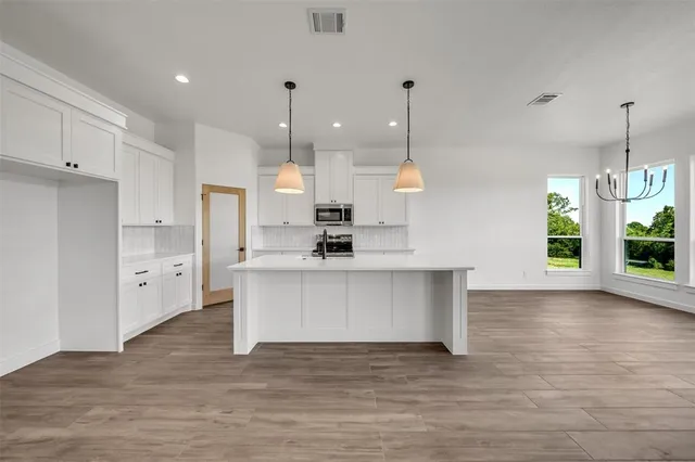 a view of a kitchen with kitchen island a sink stainless steel appliances and cabinets