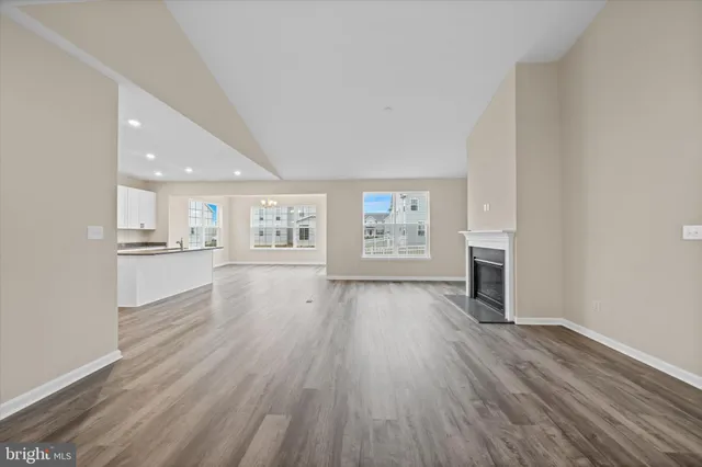 an empty room with wooden floor and kitchen view