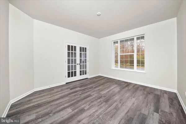 a view of an empty room with wooden floor and windows
