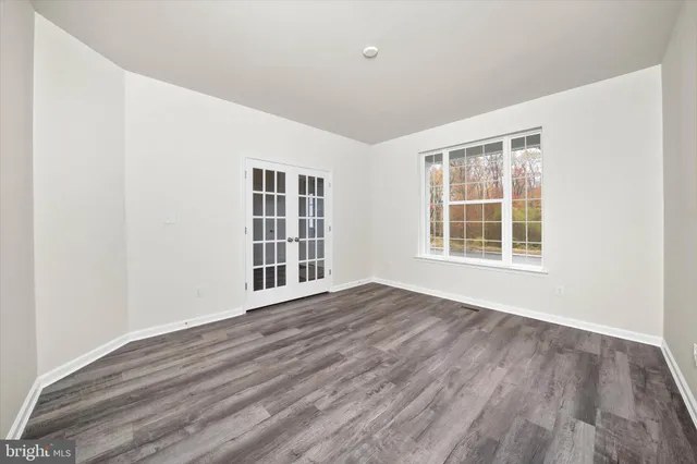 a view of an empty room with wooden floor and windows