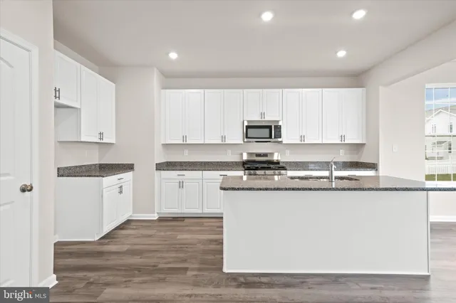 a kitchen with kitchen island granite countertop white cabinets and white appliances