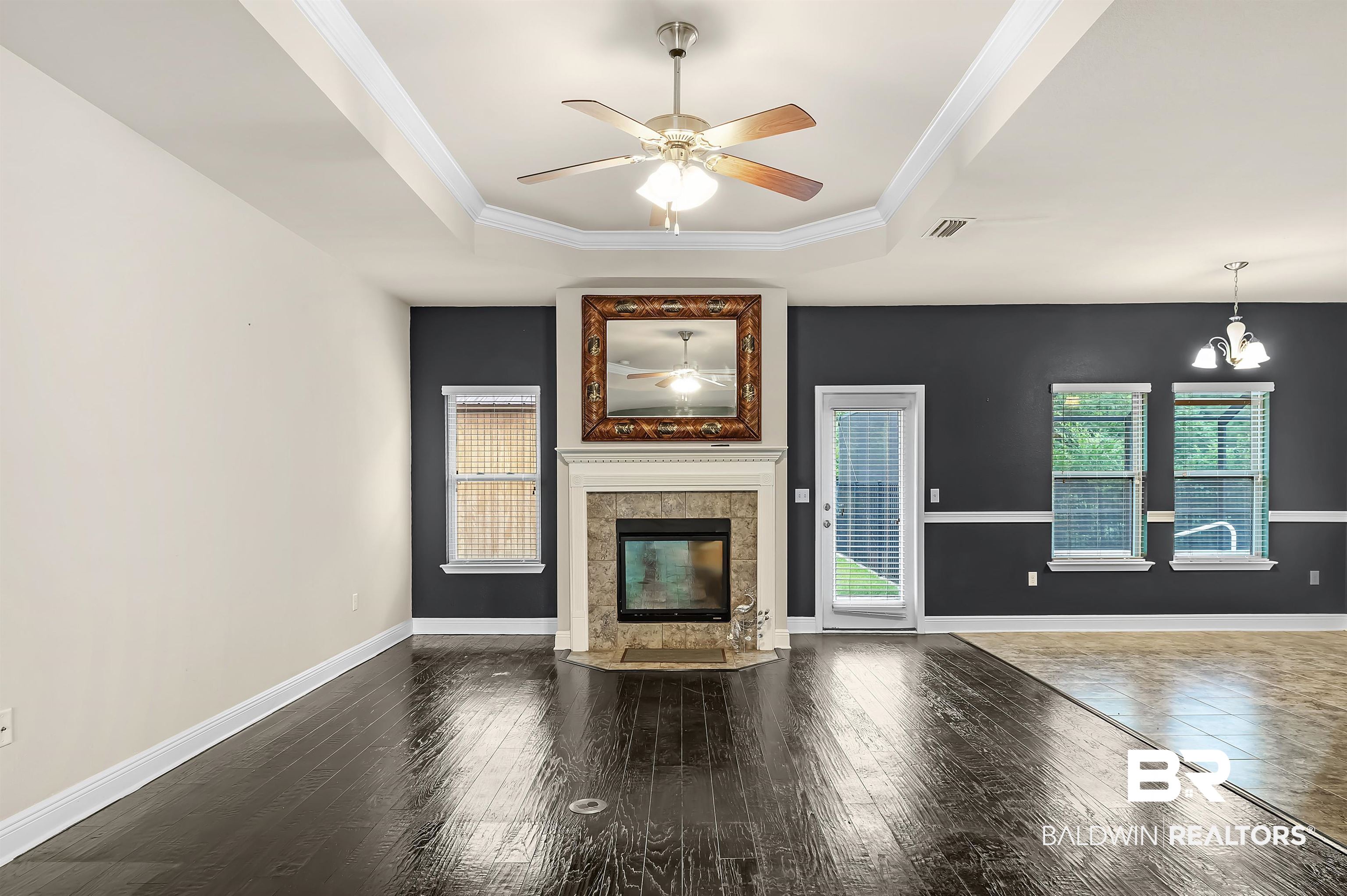 1086 Melbourne Court Foley, AL 36535 - Photo 8 of 43 Unfurnished living room featuring plenty of natural light, a tiled fireplace, a tray ceiling, and ceiling fan with notable chandelier