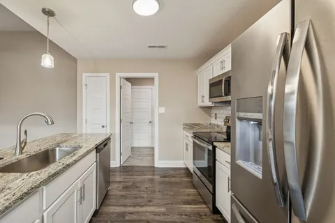 a kitchen with stainless steel appliances granite countertop a refrigerator a stove and a sink