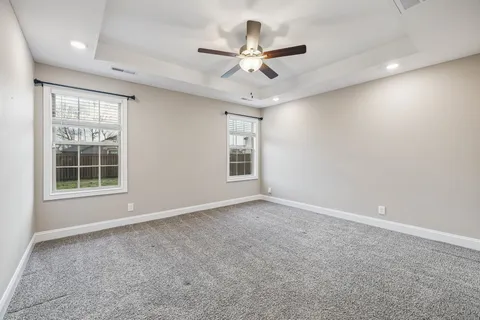 an empty room with windows and fan