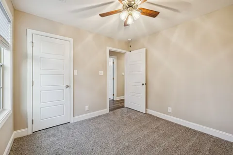 an empty room with closet and a chandelier fan