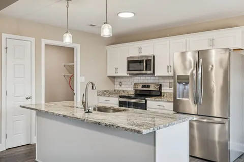 a kitchen with kitchen island granite countertop stainless steel appliances a refrigerator a stove a sink a center island and cabinets