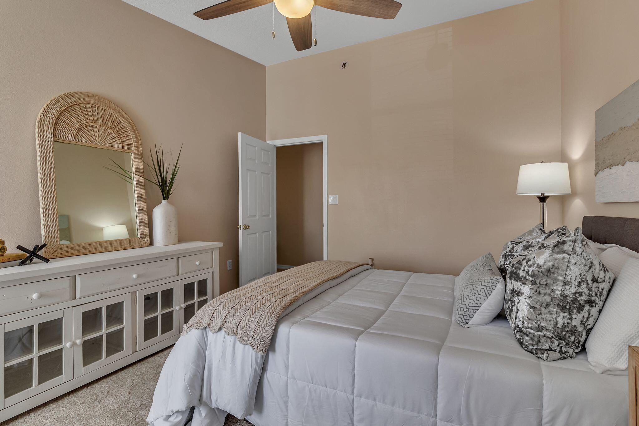 150 Bent Arrow Drive, Unit 51 Destin, FL 32541 - Photo 15 of 28 a bedroom with a bed a mirror on dresser and a chandelier