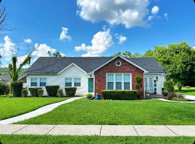 a view of house in front of a big yard with large trees