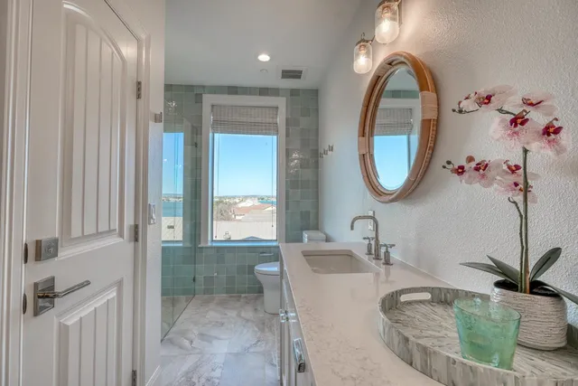 a bathroom with a granite countertop sink a mirror and shower