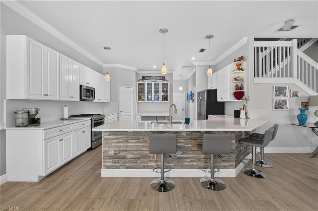 9970 Rookery Circle Estero, FL 33928 - Photo 14 of 50 Spacious kitchen featuring white cabinetry, light-toned countertops, and an island with stacked stone detailing