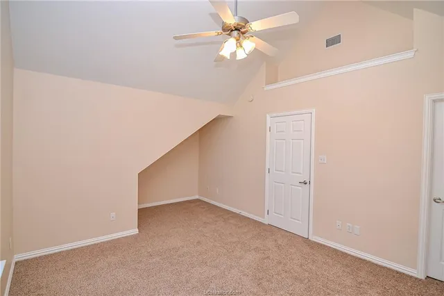 an empty room with a fan & a ceiling fan