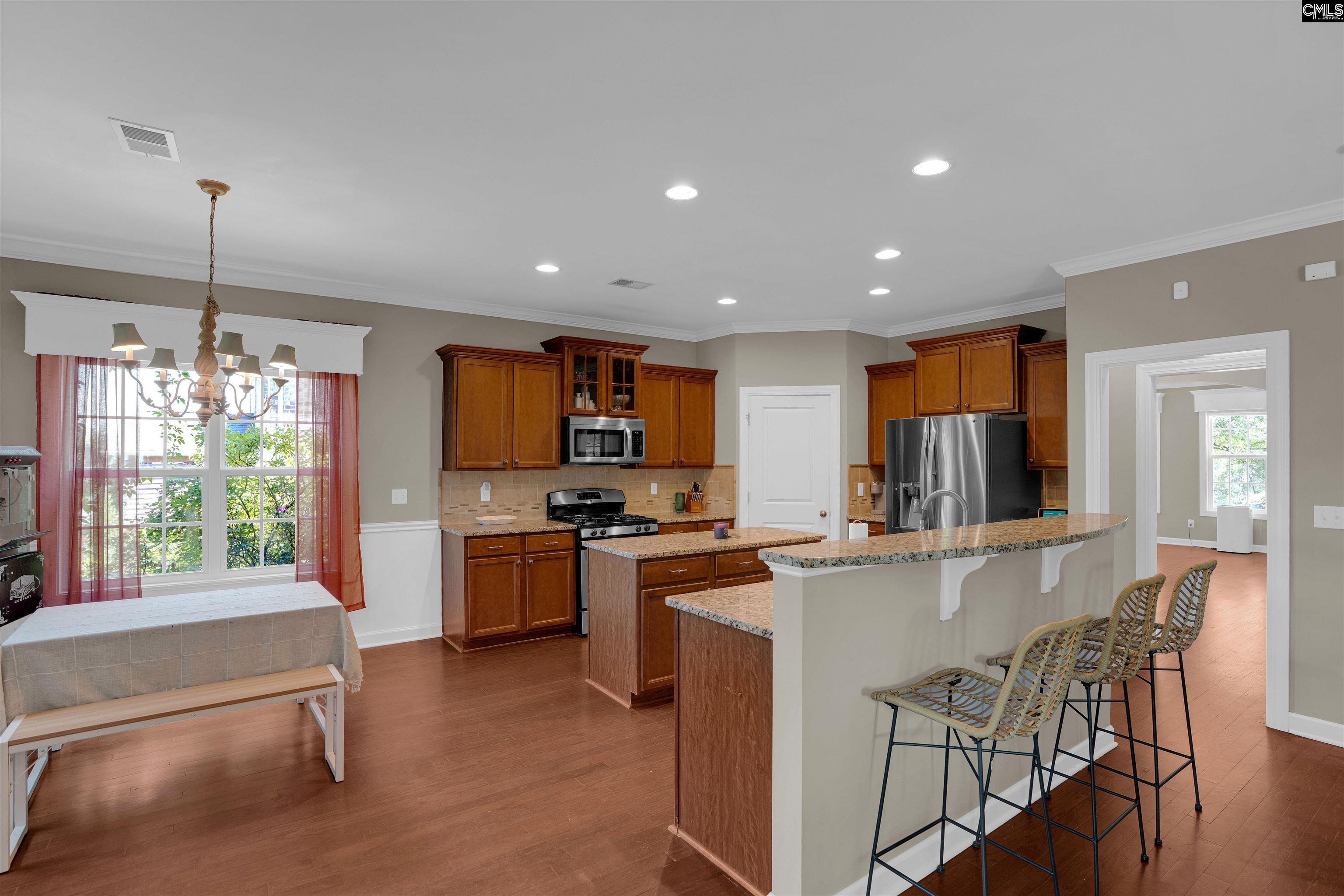 321 Asa Rose Lexington, SC 29072 - Photo 12 of 52 a kitchen with stainless steel appliances granite countertop a stove top oven a sink dishwasher a dining table and chairs with wooden floor