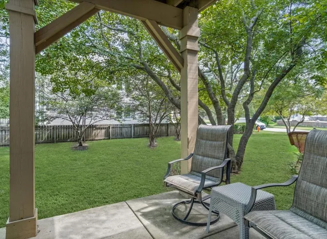 a view of a backyard with table and chairs potted plants and a large tree