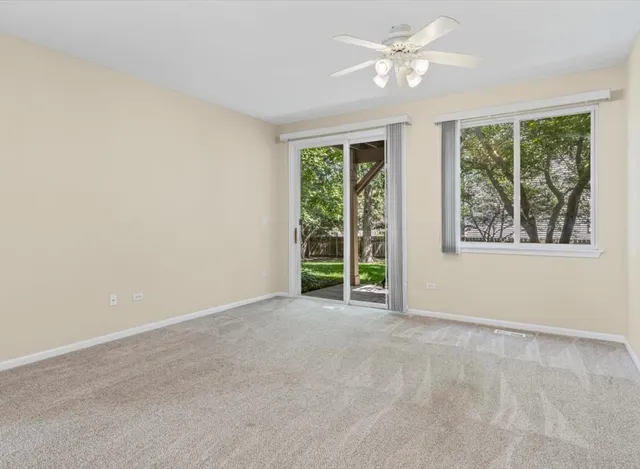 an empty room with windows and ceiling fan
