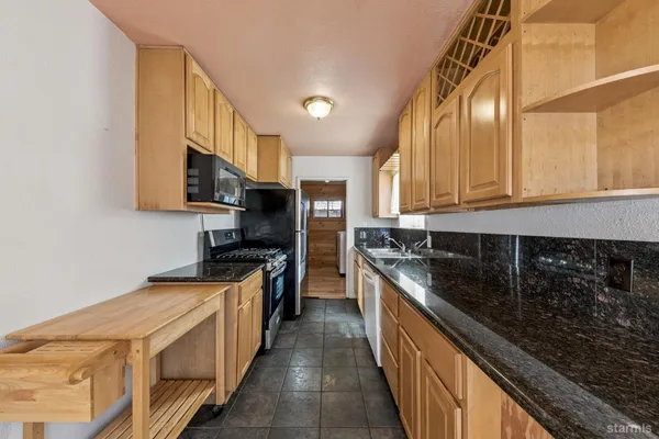 a kitchen with stainless steel appliances granite countertop a sink a stove top oven a counter space and cabinets