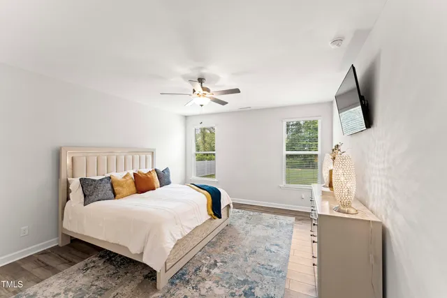 a bedroom with a large bed and a flat tv screen on dresser