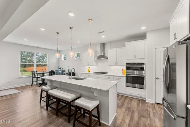 a kitchen with stainless steel appliances granite countertop a kitchen island hardwood floor sink stove dining table and chairs