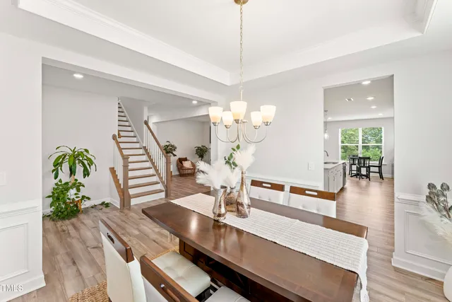 a view of a dining room and livingroom with furniture wooden floor a chandelier