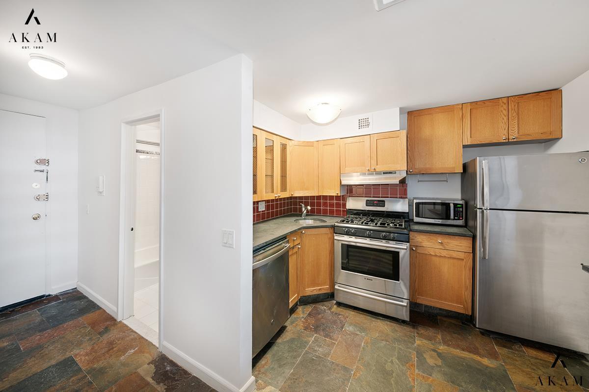 211 Thompson Street, Unit 4C Manhattan, NY 10012 - Photo 10 of 15 a kitchen with stainless steel appliances granite countertop a refrigerator and a stove top oven