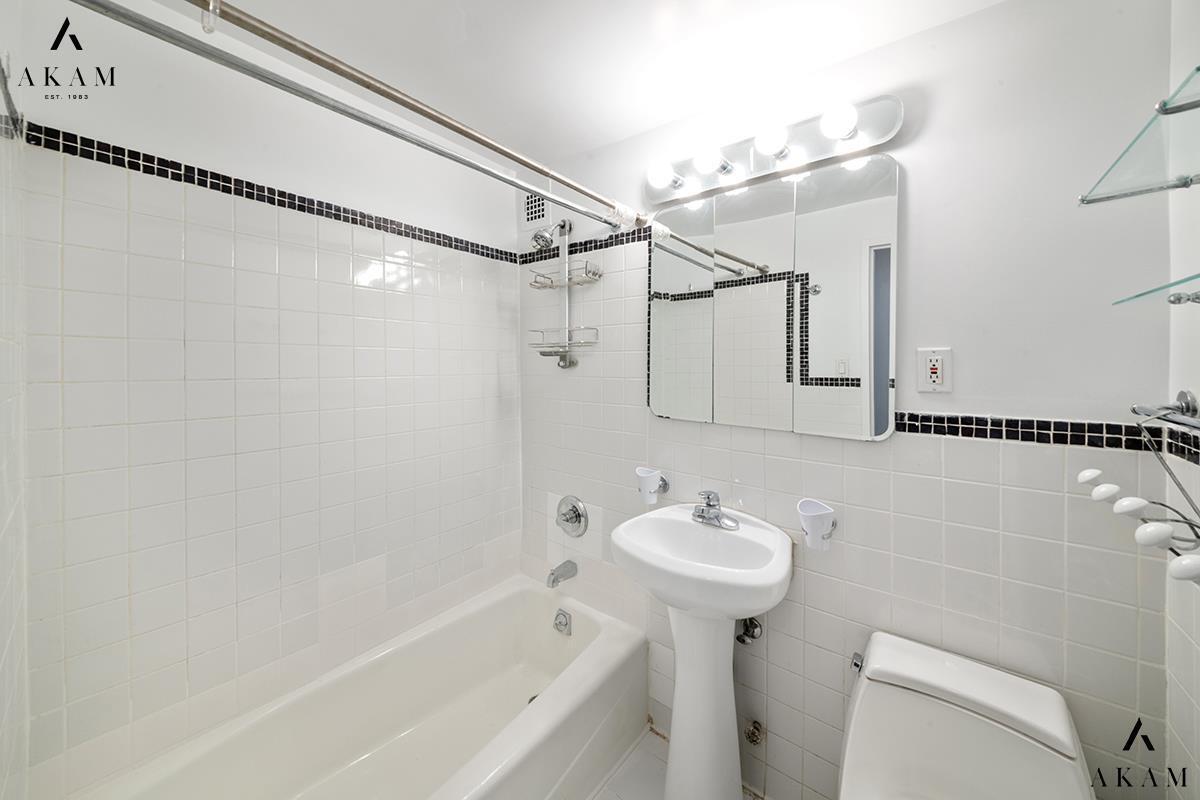 211 Thompson Street, Unit 4C Manhattan, NY 10012 - Photo 12 of 15 a bathroom with a sink a mirror toilet and bathtub