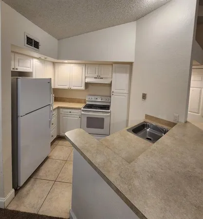 a kitchen with granite countertop a refrigerator sink and stove