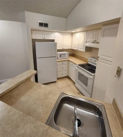 a kitchen with a refrigerator sink and cabinets