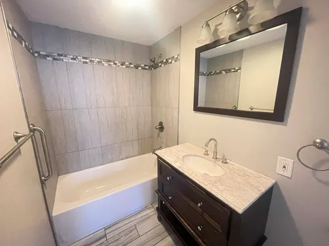 a bathroom with a tub sink and mirror