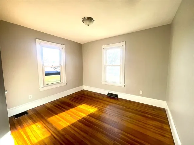 a view of an empty room with window and wooden floor
