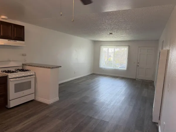 a view of an empty room with a window and wooden floor