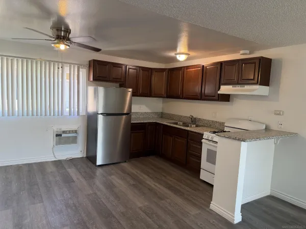 a kitchen with stainless steel appliances granite countertop a refrigerator a sink dishwasher a stove and a microwave oven on the wooden floor