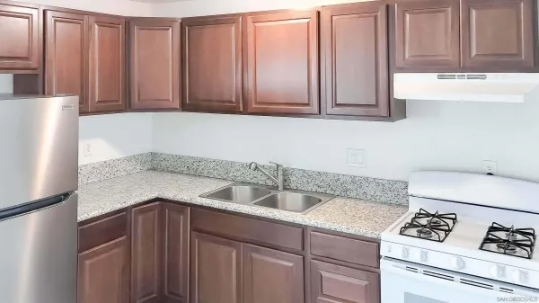 a kitchen with stainless steel appliances granite countertop white cabinets a refrigerator and a sink