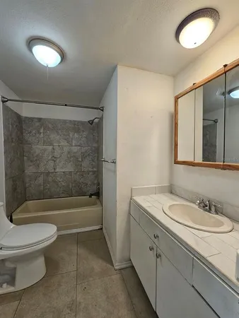 a bathroom with a granite countertop sink a toilet and shower