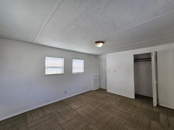 a view of an empty room with wooden floor and closet