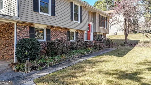 a view of a brick house with many windows plants and large trees